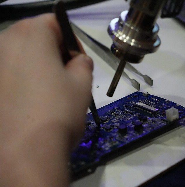 Hand soldering a circuit board under a microscope